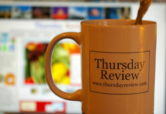 Thursday Review coffee mug in front of computer